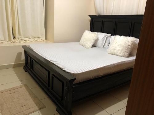 Bett mit weißen Kissen auf einem Zimmer in der Unterkunft PASWELL'S HOMES 3 Bedroom Apartment at Greatwall Gardens in Athi River