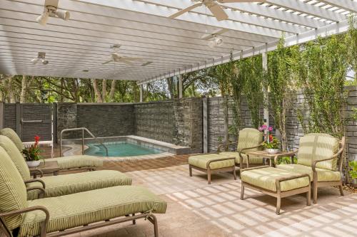an outdoor patio with a pool and chairs and a pergola at Marriott's Cypress Harbour Villas in Orlando