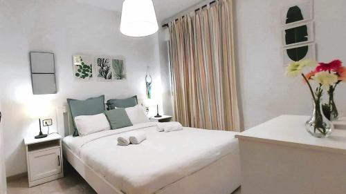 ein weißes Schlafzimmer mit einem großen Bett mit Blumen darauf in der Unterkunft Confortable vivienda en La Laguna a 5 MIN tranvía in La Laguna