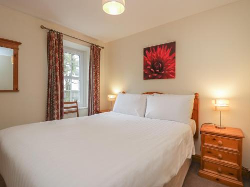 a bedroom with a large white bed and a window at Riverside Cottage No 5 in Keswick