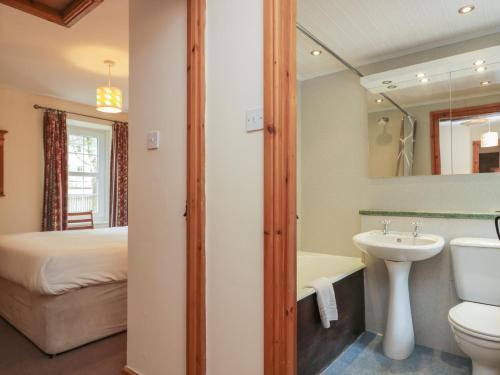a bathroom with a sink and a toilet and a bed at Riverside Cottage No 5 in Keswick