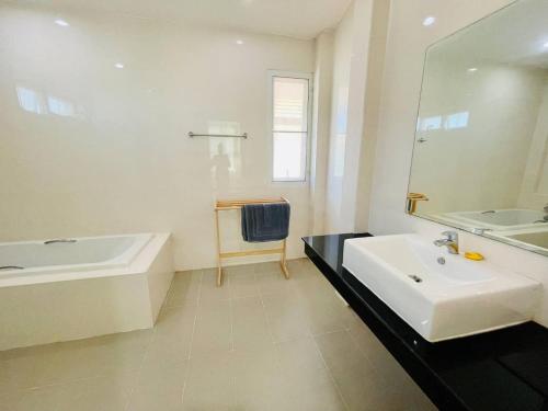 uma casa de banho com um lavatório, uma banheira e um espelho. em Chomdao house98 em Udon Thani