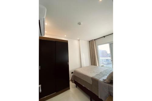 a bedroom with a bed and a large window at Apartamento Boqueirao Proximo a Praia, com Piscina in Praia Grande