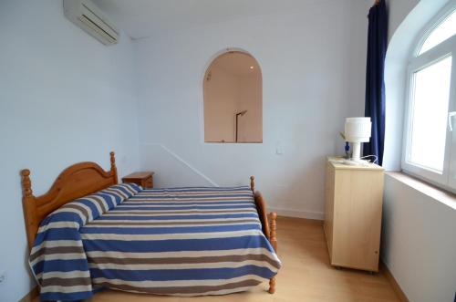 een slaapkamer met een bed met een blauw en wit gestreepte deken bij Villa Narcol in L'Estartit