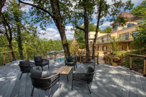 a deck with chairs and tables and a tree at La Perle de Domme in Sarlat-la-Canéda