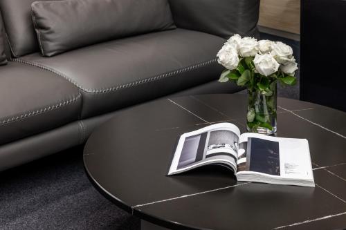 a coffee table with a vase of flowers and a book at Derand Hotel in Pristina