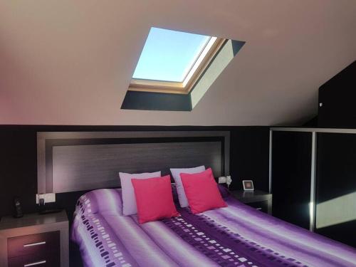 een slaapkamer met een paars bed en een dakraam bij Chalet con piscina en O Rosal in Rosal