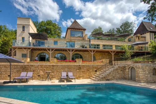 a house with a swimming pool in front of a building at La Perle de Domme in Sarlat-la-Canéda