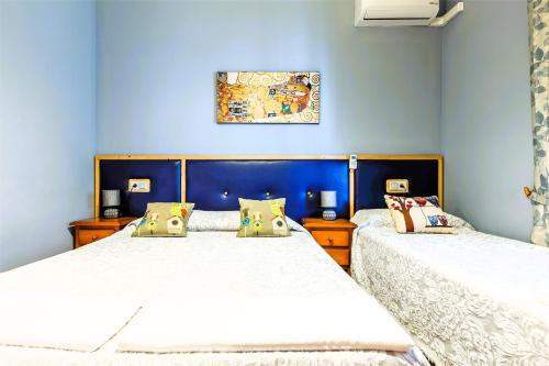 Dos camas en un dormitorio con paredes azules. en CASA RURAL VILLAMAYNO, en Alcaucín