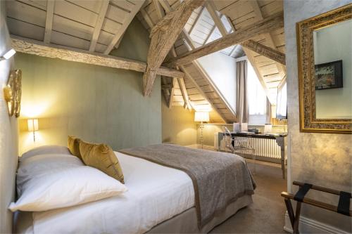 a bedroom with a bed and a table in a room at Hotel Le Place d'Armes - Relais & Châteaux in Luxembourg