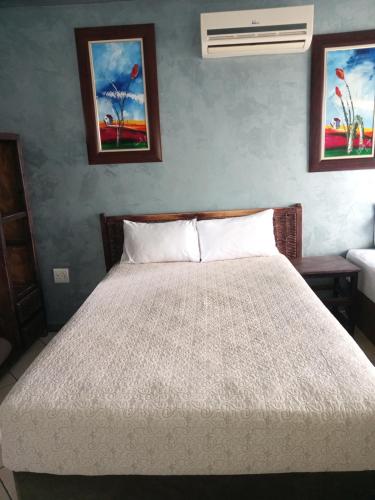 a bed in a bedroom with two pictures on the wall at Petra Lodge in Edenvale