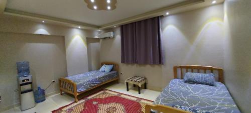Kleines Zimmer mit 2 Betten und einem Teppich in der Unterkunft Pyramids2 , Flat 309 ,2 Al Mansoureya Rd, Al Haram, Giza Governorate in Kairo