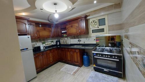 eine Küche mit Holzschränken und einem Herd mit Backofen in der Unterkunft Pyramids2 , Flat 309 ,2 Al Mansoureya Rd, Al Haram, Giza Governorate in Kairo