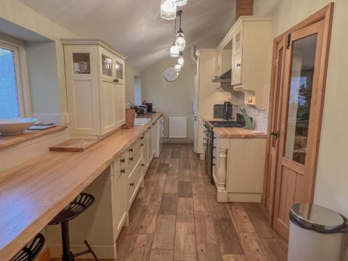 a kitchen with white cabinets and a wooden floor at Sunny Dene Cottage in Knapton