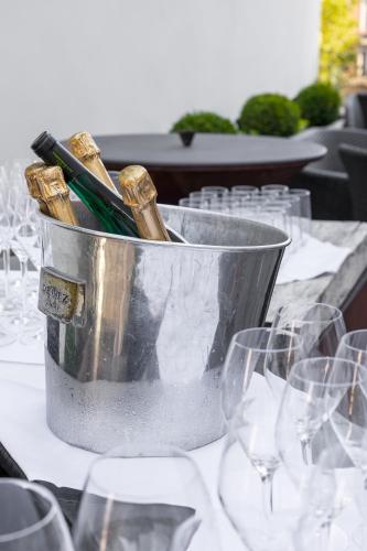 a bucket of champagne on a table with wine glasses at Hotel Le Place d'Armes - Relais & Châteaux in Luxembourg