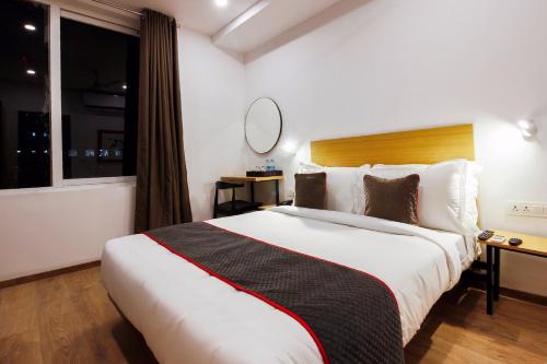 a hotel room with a large bed and a mirror at Super Townhouse RCC Elite in Hyderabad