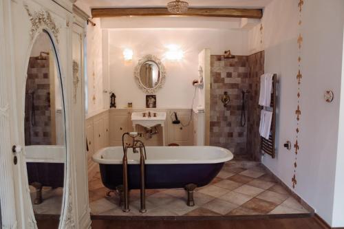 ein großes Bad mit einer Badewanne und einem Spiegel in der Unterkunft Dolce Vita Villa in Zalahaláp