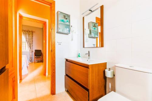 Un baño con lavabo, inodoro y espejo. en CASA RURAL VILLAMAYNO, en Alcaucín