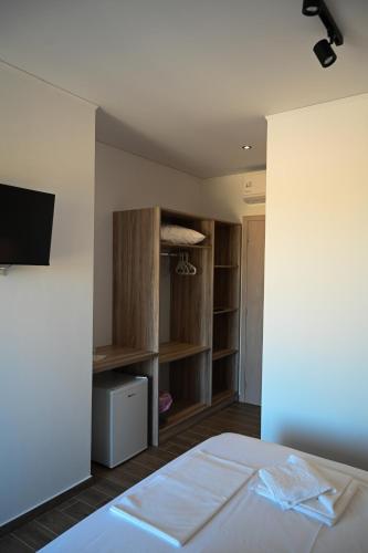 a bedroom with a bed and a tv and shelves at Costa Varda Apartments in Mourteri