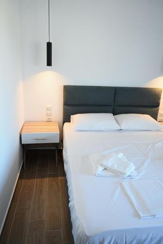 a bedroom with a white bed and a night stand at Costa Varda Apartments in Mourteri
