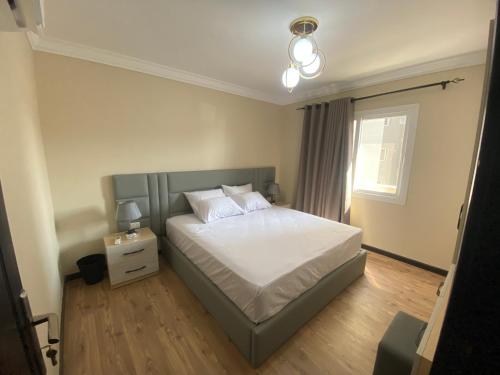 1 dormitorio con 1 cama con sábanas blancas y ventana en شقة فندقية في منتجع اوشن بلو en El Cairo