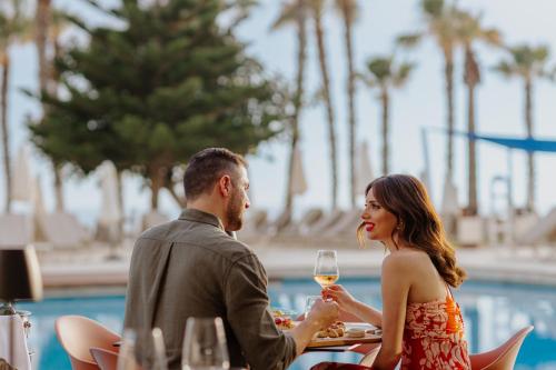 a man and woman sitting at a table with a glass of wine at Louis Ledra Beach in Paphos City