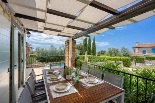 a patio with a wooden table and chairs on a balcony at Vila Aryana With Pool - Happy Rentals in Sveti Lovreč Pazenatički