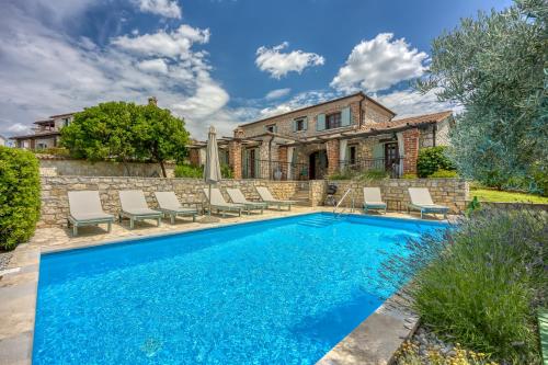 a swimming pool with chairs and a house at Vila Aryana With Pool - Happy Rentals in Sveti Lovreč Pazenatički