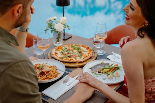 a group of people sitting around a table with pizza at Louis Ledra Beach in Paphos City