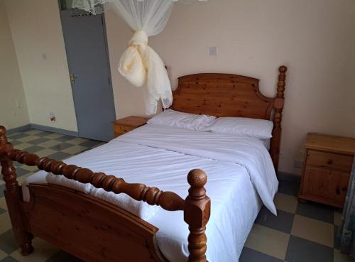 a bedroom with a wooden bed with white sheets at Mfalme House, Ngoingwa Estate, 100 Metres from Thika-Mangu Rd, Close to Thika City Centre - Free Parking, Fast Wi-Fi, Smart TV, 2 Bedrooms Perfect for a Family of 2-4 Members in Thika