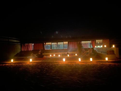 a group of people sitting around a fireplace at night at Wadi Rum Nature Stars Camp in Wadi Rum