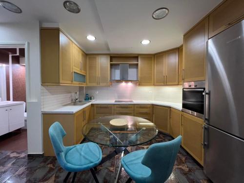 eine Küche mit einem Glastisch und zwei blauen Stühlen in der Unterkunft CELENA CITY in Kalamata