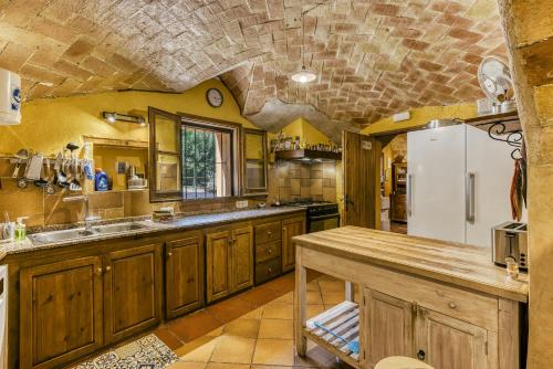 a kitchen with wooden cabinets and a white refrigerator at Mas Alba in San Esteban de Guialbes