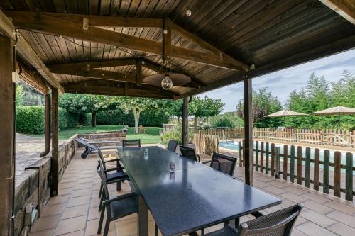 a patio with a black table and chairs and an umbrella at Mas Alba in San Esteban de Guialbes