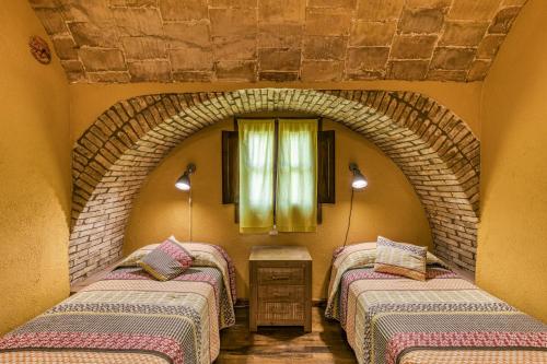two beds in a room with a brick wall at Mas Alba in San Esteban de Guialbes