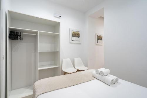 a white bedroom with a bed and two white chairs at Apartamento acogedor y cómodo GUAD-C in Madrid