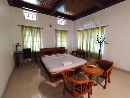 1 dormitorio con 1 cama, mesa y sillas en AZZA Heritage Home, en Kochi