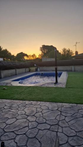 a swimming pool in a park with the sunset in the background at Chalet con piscina en escalona in Toledo