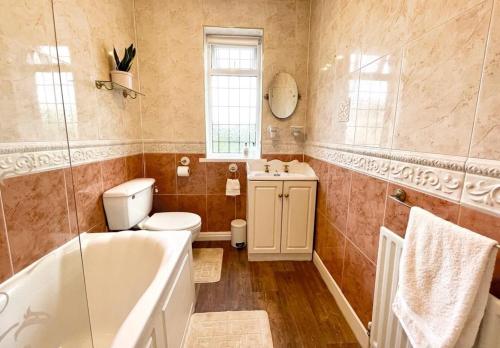 e bagno con vasca, servizi igienici e lavandino. di Cosy Croft Cottage a Greasbrough