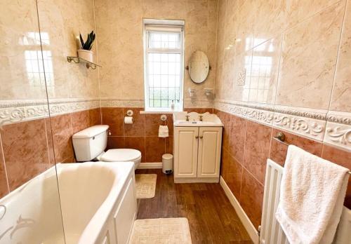 a bathroom with a tub and a toilet and a sink at Cosy Croft Cottage in Greasbrough