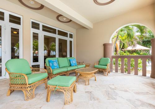 a porch with chairs and tables and a balcony at Belizean Cove Estates Beachfront Villas in San Pedro