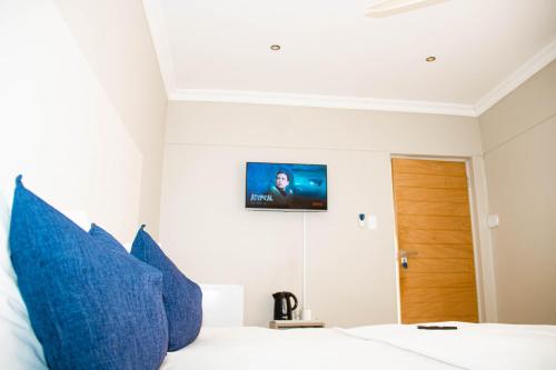 a bedroom with blue pillows and a tv on the wall at Amabwe Guesthouse in Grahamstown