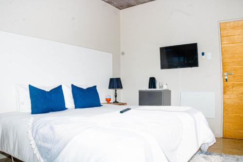 a white bed with blue pillows in a bedroom at Amabwe Guesthouse in Grahamstown