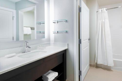 a bathroom with a sink and a mirror and a shower at Residence Inn Tampa Sabal Park/Brandon in Tampa