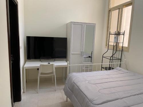 a bedroom with a bed and a desk with a television at Your Luxury Studio near Airport in Abu Dhabi