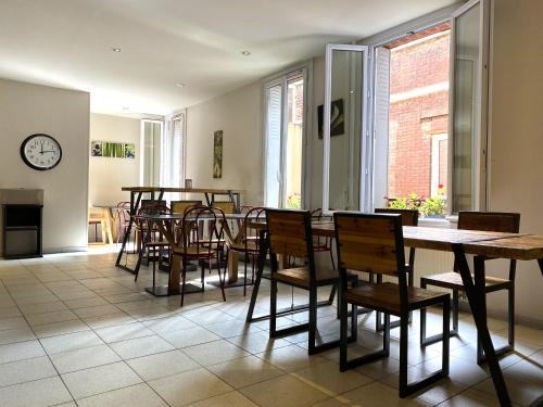 a dining room with tables and chairs and a clock at Timhotel Boulogne Rives de Seine in Boulogne-Billancourt