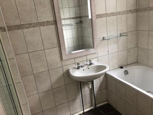 a bathroom with a sink and a tub and a mirror at @7 Mitford in Morganʼs Bay