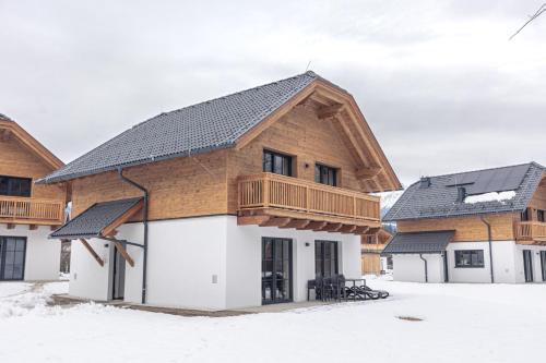 a house with a wooden roof in the snow at AlpiNest Feriendorf Lungau in Mariapfarr