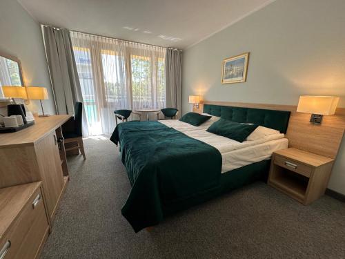 a bedroom with a large bed with a green blanket at Hotel ***NAT Świnoujście in Świnoujście