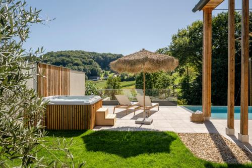 a patio with two chairs and an umbrella and a swimming pool at Julianhof Premium Guesthouse & Spa in Straden